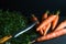 Orange carrots, leaves and a knife on a dark blue background