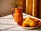 orange ceramic jug with flowers and orange plate with lemons on table with white tablecloth