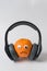 Orange character with eyes and sad smile in big headphones. Very loud concept. Vertical frame