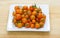 Orange cherry tomatoes displayed on white plate