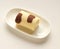 Orange chocolate roll cake in modern cream plate on cream background