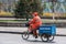 Orange clad man on tricycle collects trash, Beijing.
