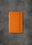 Orange closed notebook on dark concrete background