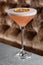 Orange Clover Club Cocktail in Coupe Glass with Layer of Foam and orange chips Garnish isolated on dark Background.