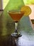 Orange cocktail in martini glass on wooden bar counter detail