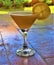 Orange cocktail with slice in martini glass on wooden outdoor bar counter detail