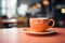 Orange coffee cup, quietly placed on a tabletop