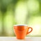 Orange coffee cup with steaming on wood desk with top copy space and green nature background refreshment breakfast