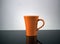 Orange coffee mug on glossy surface