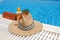 orange colored beach accessories near swimming pool. Sun cream, sunglasses, music speaker and straw hat