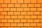 Orange colored brick wall background with black gaps