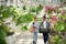 Orange colored watering device and box with plants. Florist man and woman are working together in bright greenhouse