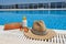 Orange coloured beach accessories near swimming pool. Sun cream, sunglasses, music speaker and straw hat