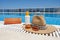 Orange coloured beach accessories near swimming pool. Sun cream, sunglasses, music speaker and straw hat