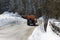 Orange-coloured Snowplough Operating on the Road with Snow on the Edges