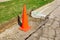 Orange cone in ditch along street ready for roadwork
