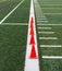 Orange cones on a green turf fields white sideline for speed training