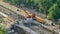 Orange construction telescopic mobile crane unloading tram rails from truck timelapse.