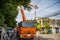 An orange crane lift sending workman with safety on a bucket to repair a light pole in the village