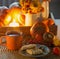 orange cup of tea and autumn decor with pumpkins, flowers and burning candles on table