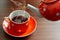 Orange cup of tea and teapot on wooden background. Hot morning drink and steam from the tea. Home tea time concept