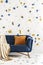 Orange cushion and blanket on blue sofa in colorful living room interior with wallpaper. Real photo
