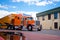 Orange custom semi truck big rig trailer drive on truck stop