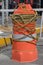 Orange cylindrical plastic structure used to control traffic.