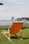 Orange deckchair in grass with view on busy river