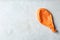 Orange deflated balloon on grey background, top view