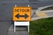 Orange detour sign with double arrow at an intersection in a residential neighborhood