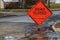 Orange diamond shaped road closure sign on road in a neighborhood near a house