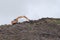 Orange digger contrasts from drab grey sky in the UK and brown surrounds. Deforesting is occurring, an environmental british