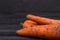 Orange dirty carrots on dark background.