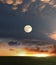 Orange dramatic sunset on wild field sun down and moon rise on starry cloudy  sky green grass nature landscape