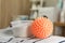 Orange dryer ball and detergent on clean clothing in laundry room, closeup