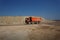 An orange dump truck, lorry full of stones in a sand quarry, transporting of materials on a natural background.