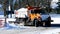 Orange dump truck with plow blade hauls a load of snow after several winter snow storms