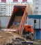 Orange dump truck unloads sand at a construction site