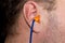 Orange earplugs in the ear in humans to reduce noise .