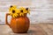 Orange earth tone pottery pitcher holding black eyed susan flowers