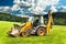 Orange Excavator on a Green Meadow. Agricultural machinery. Agricultural landscape in the Czech Republic. Bulldozer on the farm.