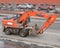 Orange excavator rides on paved road in city limits