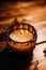 Orange fall candle resting on a wooden surface, surrounded by feathers