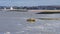 An orange fishing boat anchored in Morecambe bay in stormy weather