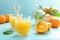 Orange freshly squeezed juice in glass and fresh fruits on a blue vivid background