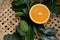 Orange fruit, fruits or vegetables half with green leaves on wicker tray closeup.