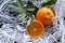 Orange fruit pile and half piece with green leaves fruits or vegetables on white shredded papers closeup.