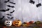 Orange ghost pumpkins with witch hat on gray wooden board background with bat. halloween concept