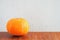 Orange gourd on wooden table on gray concrete wall background. Copy space